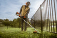 Stihl FS 131 R trimmer in use along an iron fence line